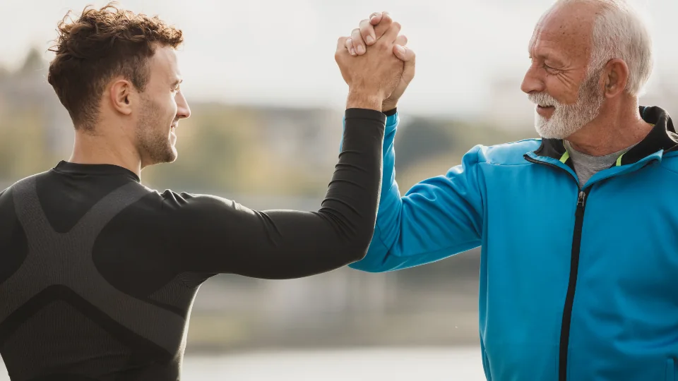 Two people clasping hands in a supportive grip, one older and one younger