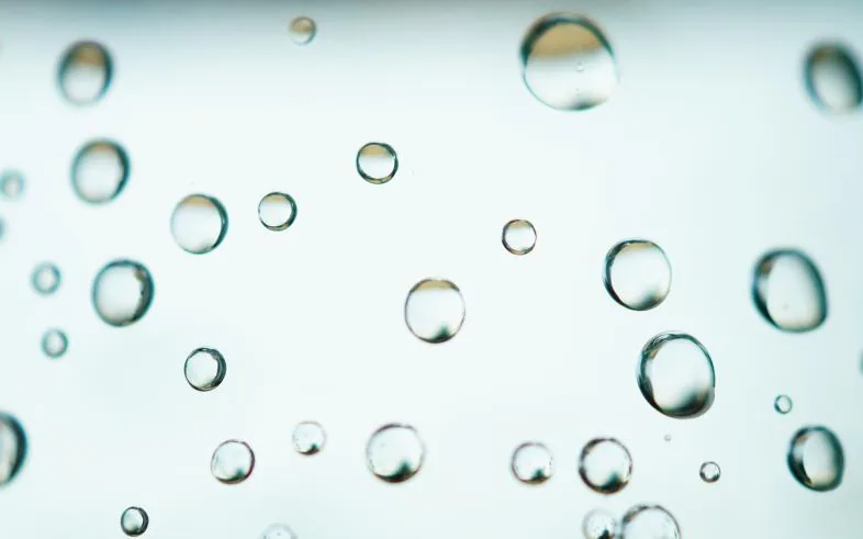 Water droplets scattered across a pale blue-green surface