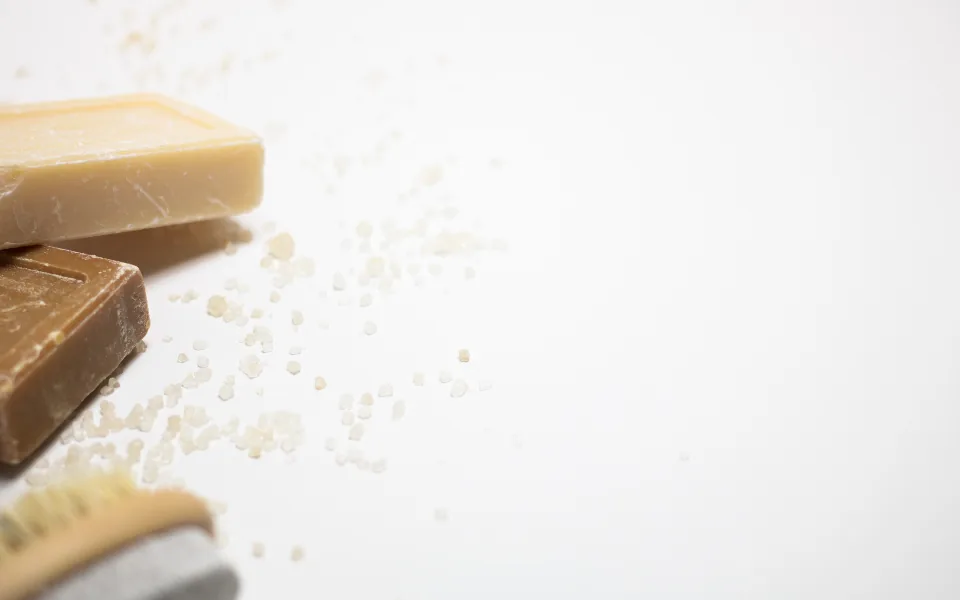 Bars of plain soap on a bright white surface, with scattered grains