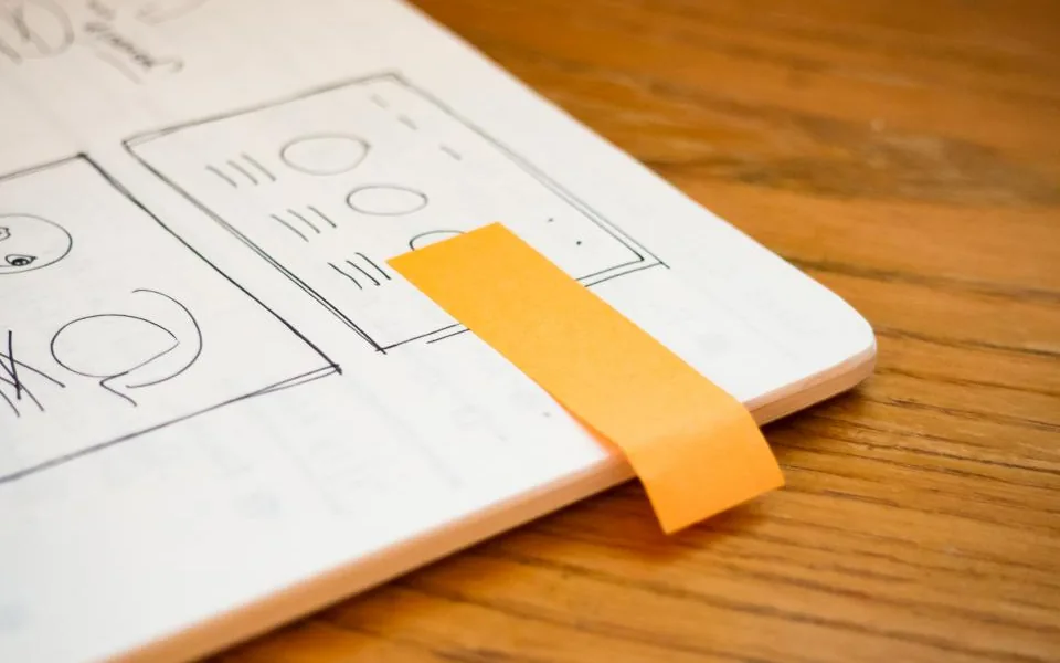 A design sketchbook marked with orange tape, open to early concept drawings