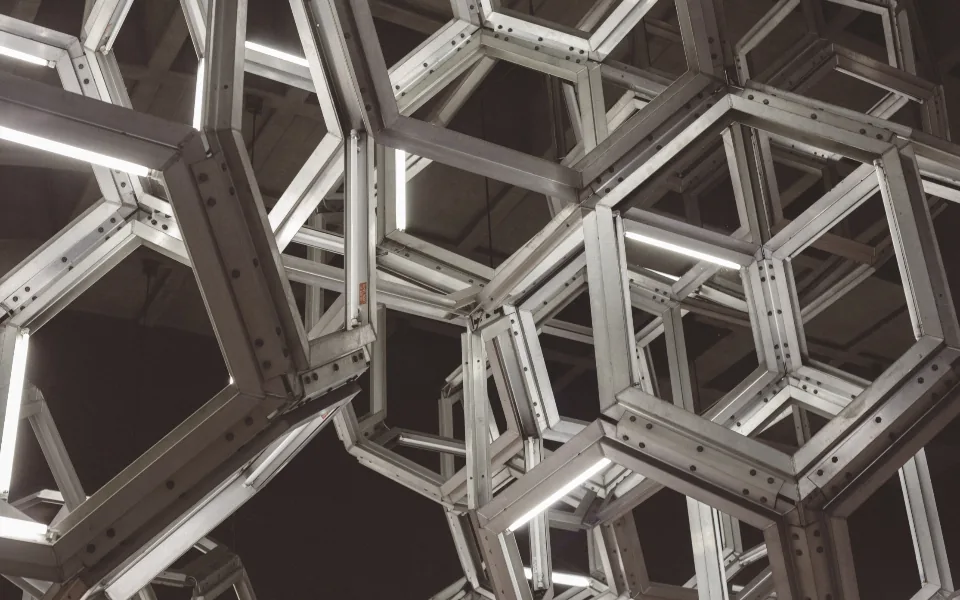 Bolted aluminium frames overhead, forming a repeating pattern of open hexagonal cells
